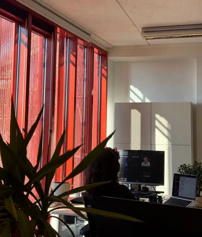 Collega van TNG Agency aan het werk op kantoor in Amsterdam, met de zon door de rode gevelpanelen