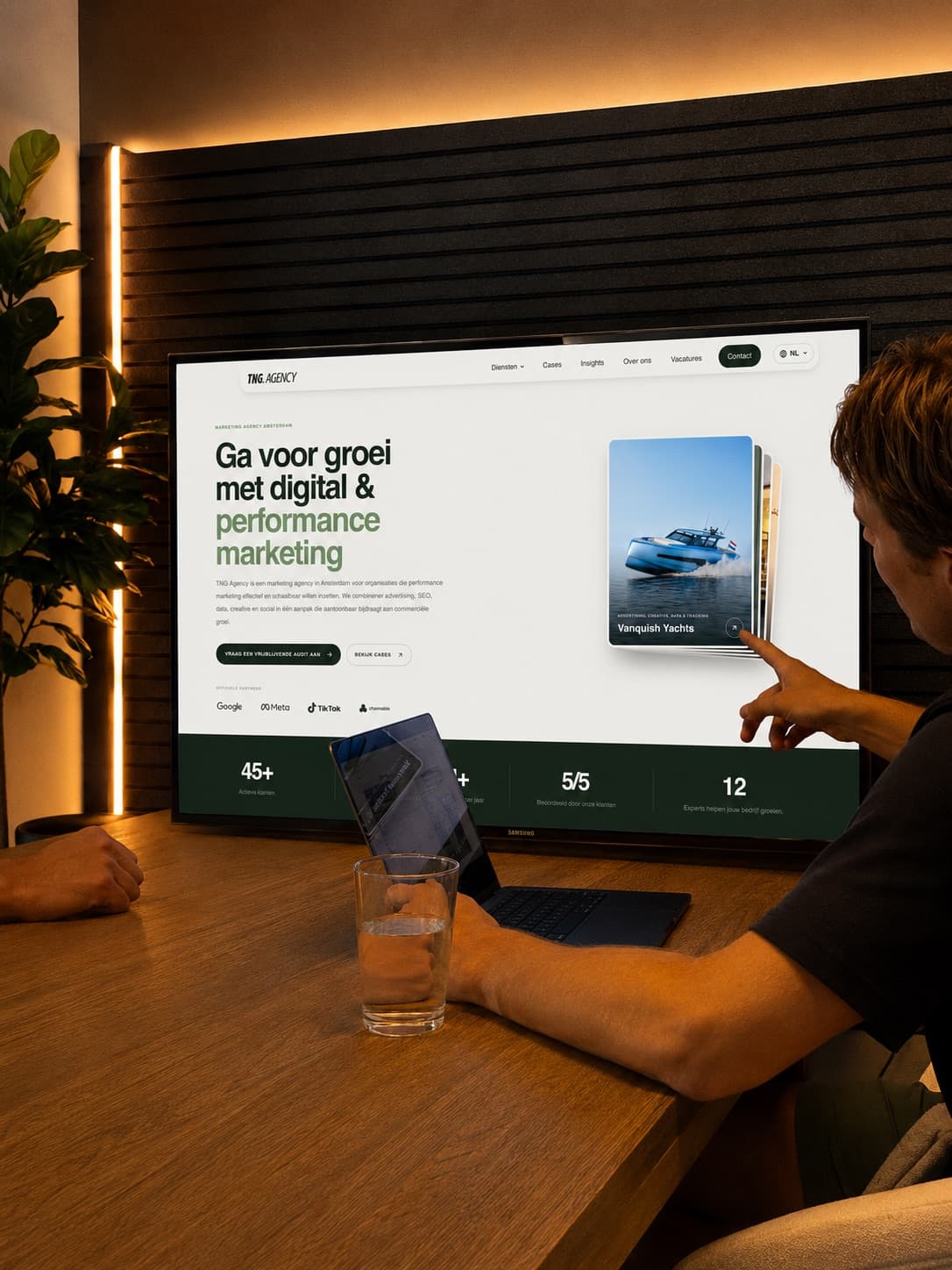 TNG specialist wijst naar de homepage van TNG Agency op een groot scherm